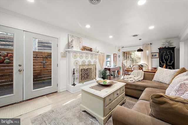 living room with plenty of natural light, light hardwood / wood-style floors, ornamental molding, and french doors