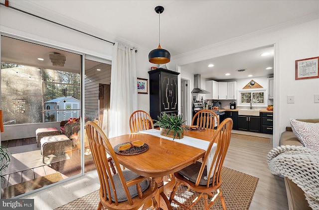 dining area with crown molding, sink, and light hardwood / wood-style floors