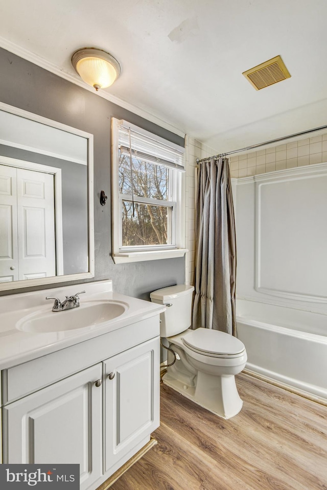 full bathroom with hardwood / wood-style floors, vanity, toilet, ornamental molding, and shower / tub combo