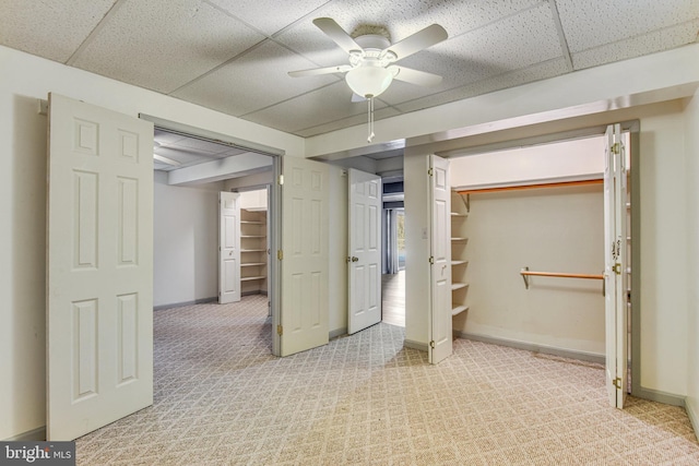 unfurnished bedroom featuring a paneled ceiling, light carpet, a closet, and ceiling fan