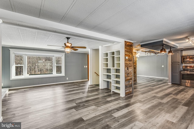 unfurnished living room featuring ceiling fan, built in features, dark wood-type flooring, and a textured ceiling