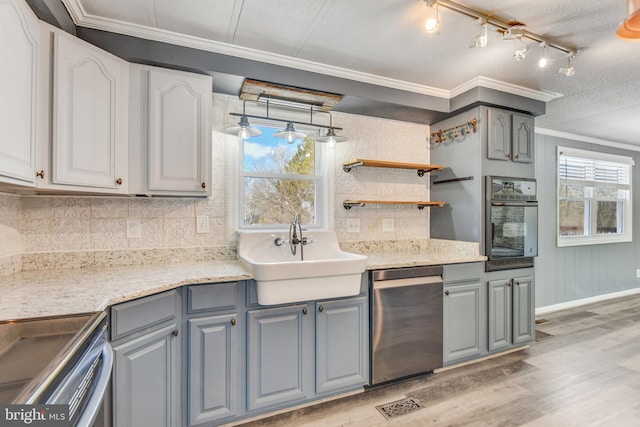 kitchen featuring rail lighting, crown molding, sink, light wood-type flooring, and wall oven