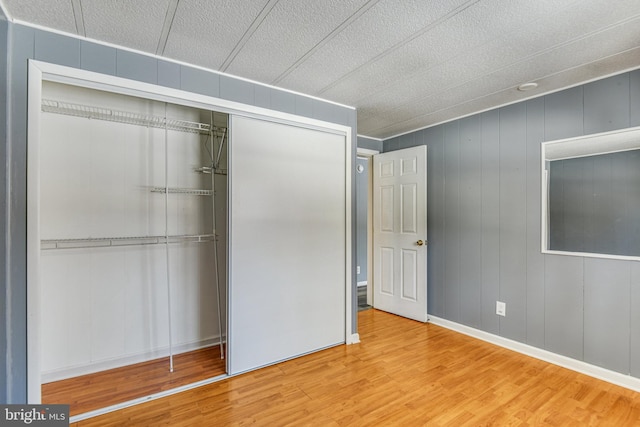 unfurnished bedroom featuring hardwood / wood-style flooring, wood walls, and a closet