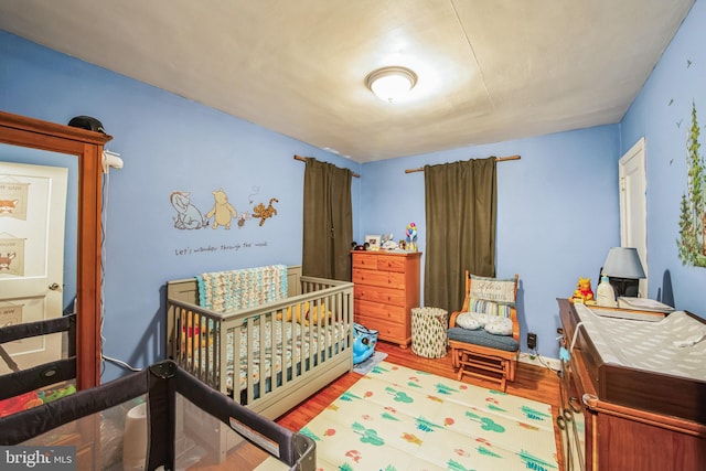 bedroom with hardwood / wood-style floors and a crib