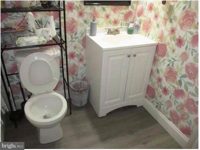 bathroom featuring wallpapered walls, toilet, vanity, and baseboards