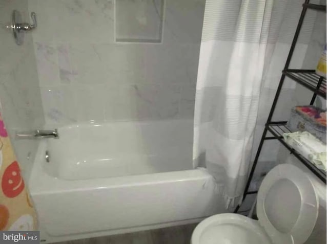 bathroom with shower / bath combo with shower curtain and toilet