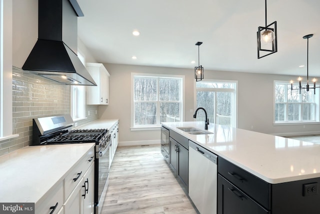 kitchen featuring white cabinets, stainless steel appliances, wall chimney exhaust hood, and sink