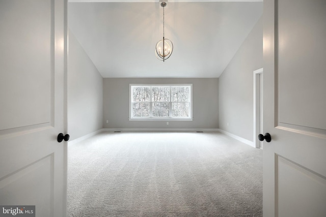 carpeted empty room featuring a chandelier and vaulted ceiling