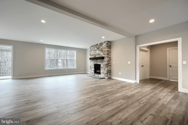 unfurnished living room with a stone fireplace and light hardwood / wood-style floors