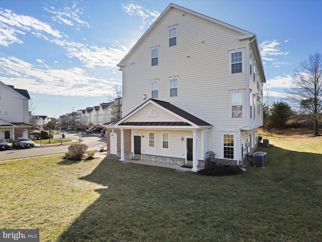 rear view of house featuring a lawn and central air condition unit