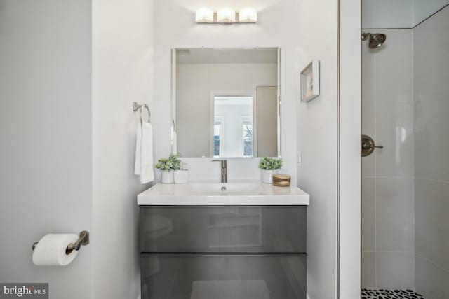 full bathroom featuring tiled shower and vanity