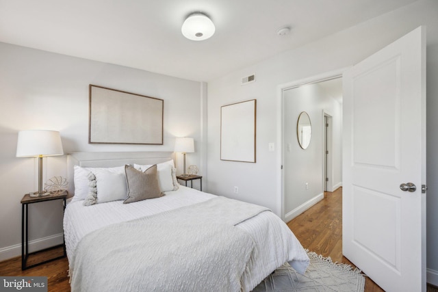 bedroom featuring wood finished floors, visible vents, and baseboards