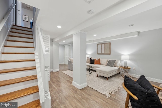 living area featuring stairs, baseboards, and light wood finished floors