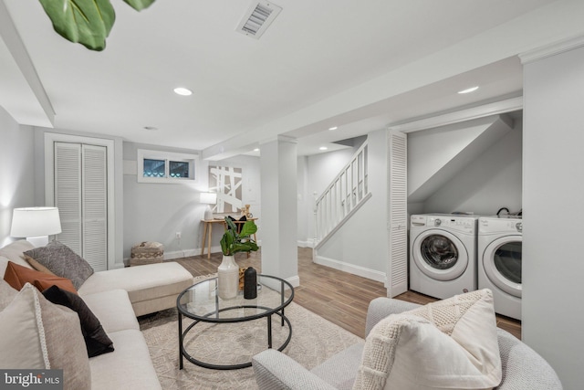 living area featuring visible vents, baseboards, washing machine and dryer, stairs, and wood finished floors