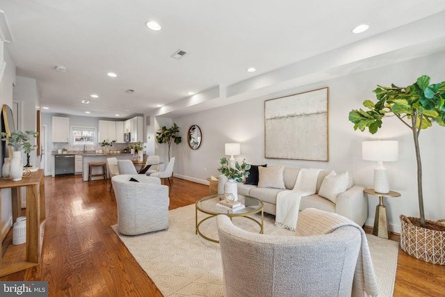 living room with recessed lighting, visible vents, and wood finished floors