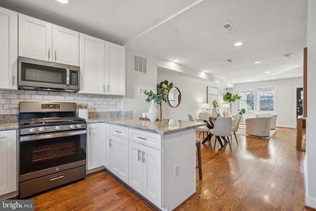 kitchen featuring visible vents, white cabinetry, a peninsula, and stainless steel appliances