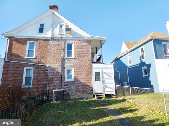 rear view of house featuring a lawn and central air condition unit