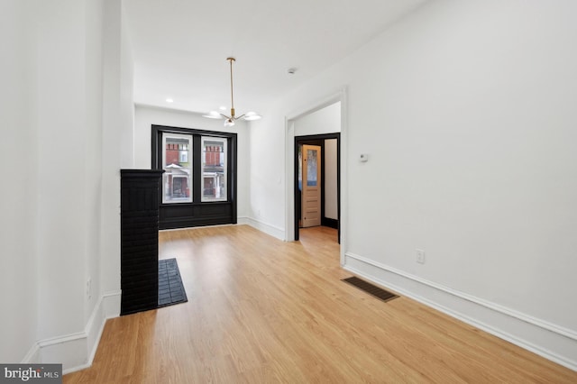 unfurnished room featuring light wood-type flooring and an inviting chandelier