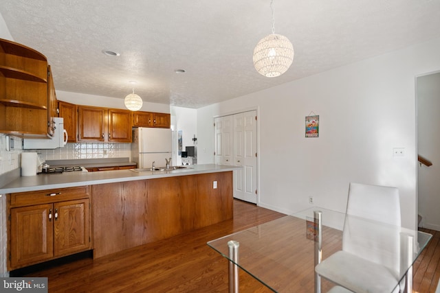 kitchen with pendant lighting, white refrigerator, decorative backsplash, dark hardwood / wood-style flooring, and a chandelier