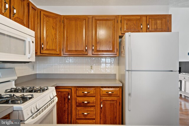 kitchen featuring decorative backsplash, white appliances, and hardwood / wood-style flooring