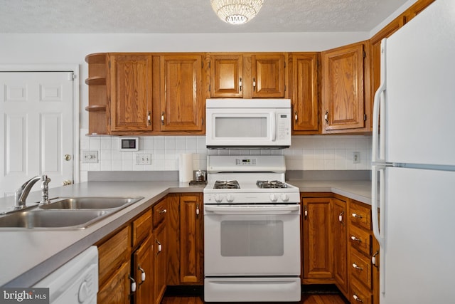 kitchen featuring a textured ceiling, decorative backsplash, sink, and white appliances