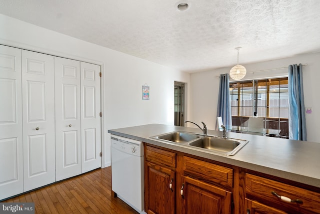 kitchen with pendant lighting, white dishwasher, sink, light wood-type flooring, and a textured ceiling