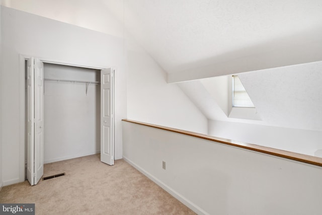 interior space with light colored carpet, a textured ceiling, and vaulted ceiling