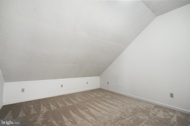 additional living space featuring carpet flooring, a textured ceiling, and vaulted ceiling