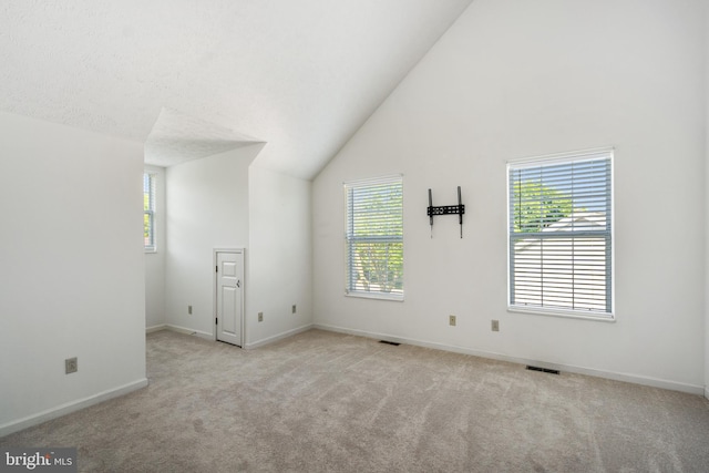 interior space featuring light colored carpet, vaulted ceiling, and a healthy amount of sunlight