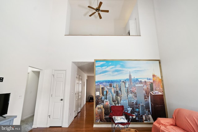 living room with a towering ceiling, dark hardwood / wood-style floors, and ceiling fan