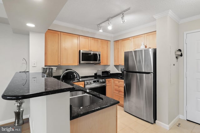 kitchen with kitchen peninsula, light brown cabinetry, stainless steel appliances, and dark stone countertops