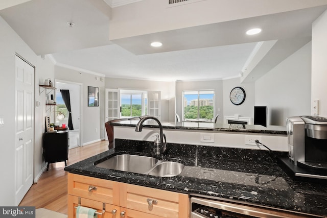 kitchen with crown molding, sink, light brown cabinets, light hardwood / wood-style flooring, and dark stone countertops