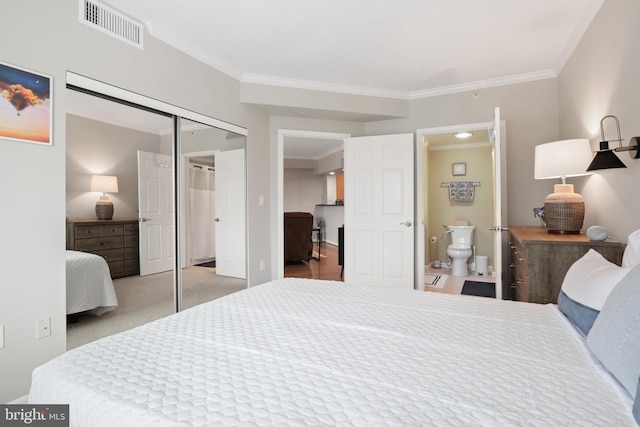 carpeted bedroom featuring ensuite bathroom, a closet, and ornamental molding