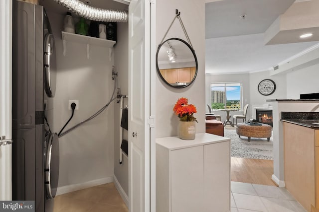 interior space with stacked washer and dryer, light tile patterned floors, and light brown cabinets