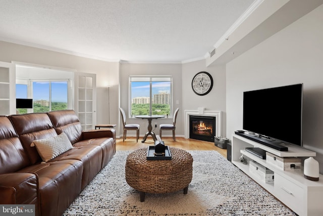 living room featuring a textured ceiling, crown molding, a wealth of natural light, and light hardwood / wood-style flooring