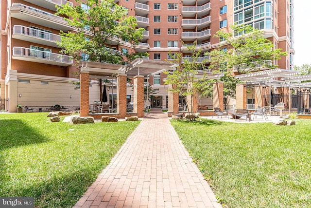 view of community featuring a pergola, a yard, and a patio