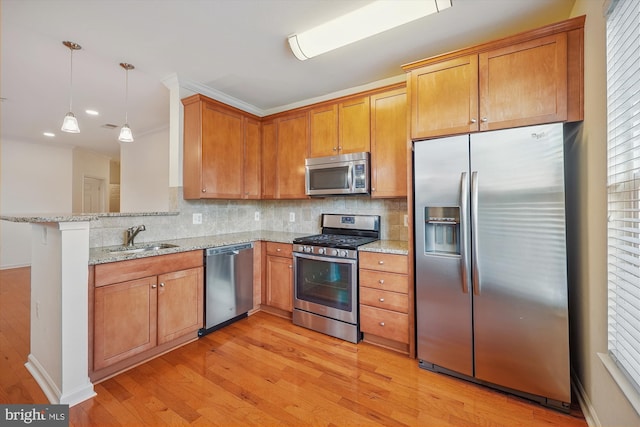 kitchen with light stone countertops, sink, stainless steel appliances, light hardwood / wood-style flooring, and kitchen peninsula