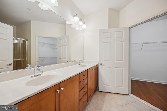 bathroom with tile patterned flooring, vanity, and walk in shower