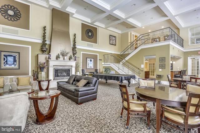 interior space with beam ceiling, a fireplace, a towering ceiling, and coffered ceiling