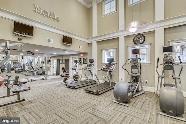 workout area featuring light colored carpet, a towering ceiling, and ornamental molding