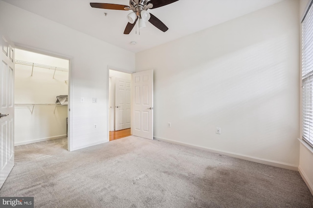 unfurnished bedroom featuring ceiling fan, a closet, light colored carpet, and a spacious closet