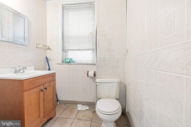 bathroom featuring tile patterned flooring, vanity, toilet, and tile walls