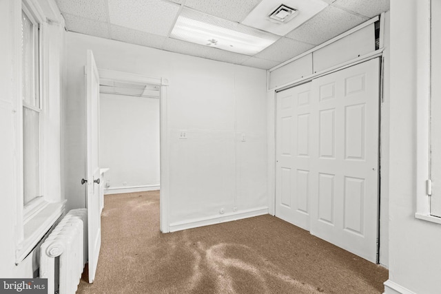 walk in closet featuring radiator, a drop ceiling, and carpet