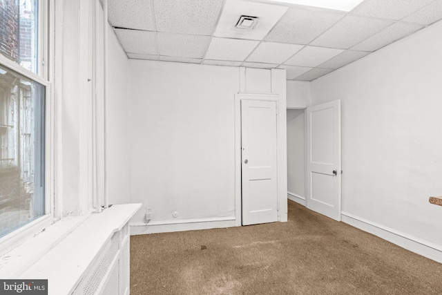 carpeted spare room with a drop ceiling