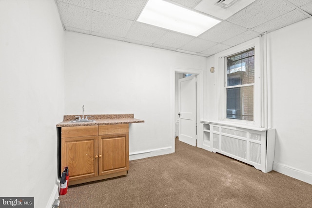 bar with a paneled ceiling, carpet flooring, sink, and radiator