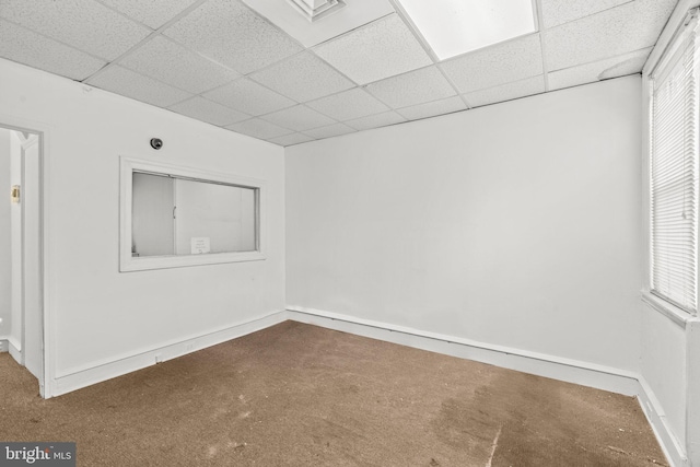 carpeted empty room featuring a drop ceiling