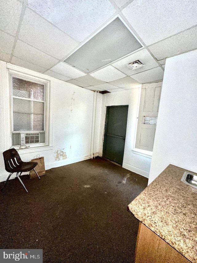 interior space featuring dark colored carpet, a drop ceiling, and cooling unit