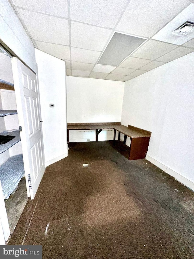 interior space with a paneled ceiling and dark colored carpet