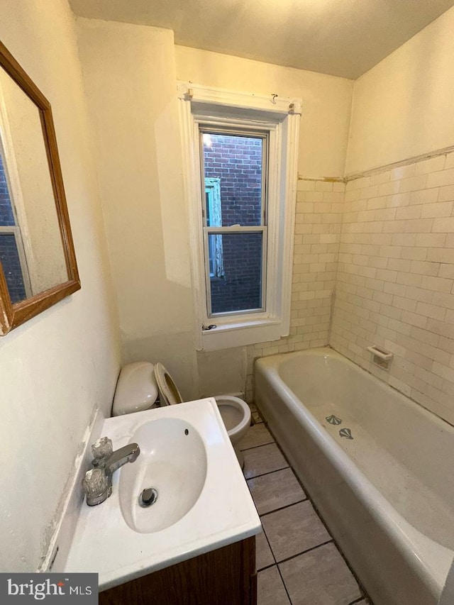 bathroom featuring tile patterned flooring, vanity, toilet, and a tub