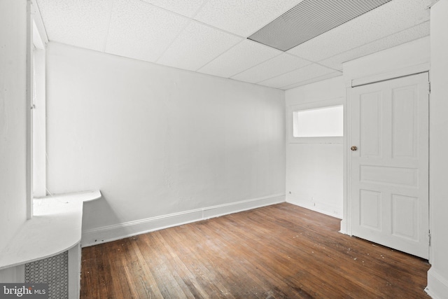 interior space featuring a paneled ceiling and dark hardwood / wood-style flooring